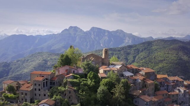 Mountain Village in Liguria: Drone View of Italy&rsquo;s Green Hills and Mountain Panorama on a Bright Day with Blue Sky &ndash;  Drone Flyover Tracking Left