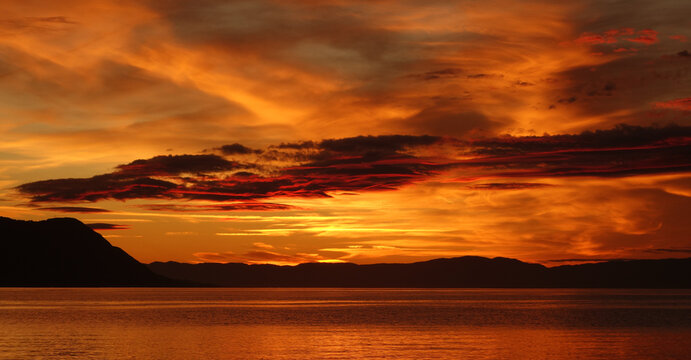 Fiery Sunset Over Calm Waters with Dramatic Cloudscape