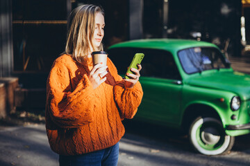 Woman in Cozy Knitted Orange Sweater Enjoying Coffee Outdoors