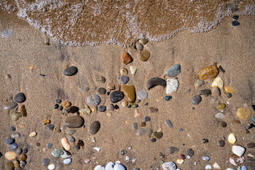 Stones and water on the sandy beach.