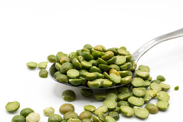 An overflowing spoonful of dried split peas on a white background.