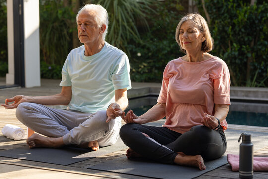 Senior couple meditating outdoors on yoga mats, enjoying peaceful morning - Powered by Adobe