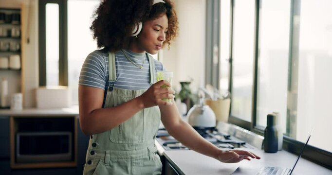 Morning, dance and laptop with woman and smoothie for streaming, nutrition or social media. Cooking blog, kitchen and wellness with person and headphones in home for internet, health or online recipe