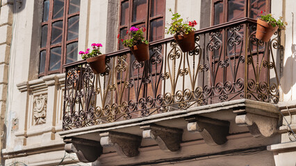 Charming balcony with wrought iron railing and flower pots on an old colonial building facade.