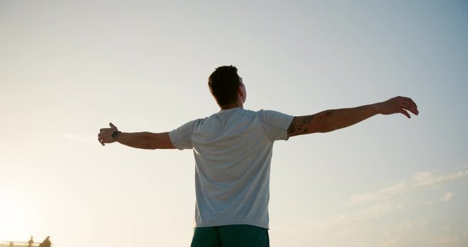 Man, back and breathing with fitness on beach for peace, health and wellness by sea in nature. Male person, athlete and arms out for freedom, breeze or natural fresh air with blue sky on ocean coast
