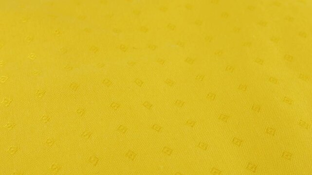 Top view of biscotti yellow cotton fabric rotated on the display case. Textile background on the theme of sewing clothes, design, fashion.