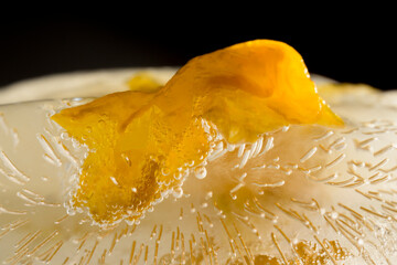 Macro photography of yellow flower frozen in ice in horizontal details of the flower and the ice
