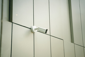 A sleek, modern surveillance camera has been installed on the exterior facade of a contemporary building design