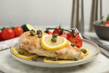 Delicious cooked chicken fillet with capers, tomatoes and lemon on table, closeup