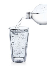 Pouring soda water from bottle into glass on white background