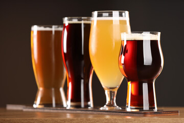 Glasses with different types of beer on wooden table indoors, closeup