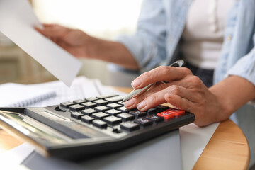 Budget planning. Woman using calculator while working with accounting document at table indoors,...