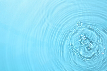 Rippled surface of clear water on light blue background, top view