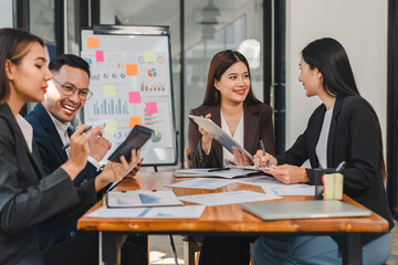 Collaborative business meeting with professionals discussing strategies and analyzing data. Engaged team members share ideas using tablets and documents, fostering productive environment