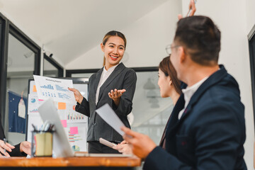 Business presentation with confident woman sharing marketing report data to engaged colleagues in modern office setting, showcasing teamwork and collaboration