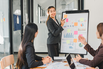 businesswoman presents data on whiteboard to colleagues in modern office. team engages with charts and graphs, showcasing collaboration and professionalism