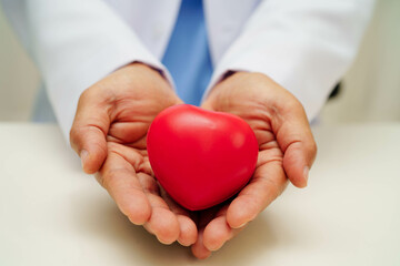 Asian woman doctor holding red heart for health in hospital.