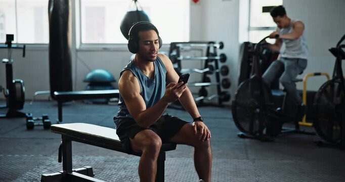 Man, gym and break with on smartphone with headphones for fitness motivation, audio or music. Male person, body builder and streaming radio or subscription on internet, website or online for playlist