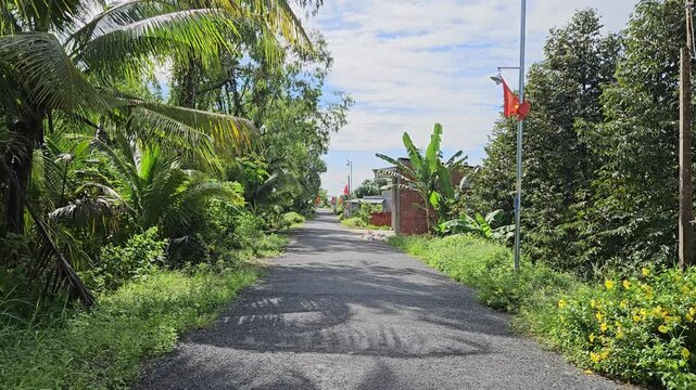 POV on narrow street in the village at Mang Thit district, Vinh Long province, Mekong Delta Vietnam in the morning.