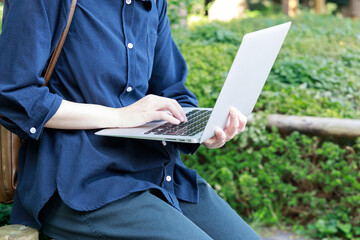 公園でノートパソコンを使用している女性　屋外　仕事　イメージ