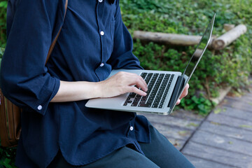 公園でノートパソコンを使用している女性　屋外　仕事　イメージ