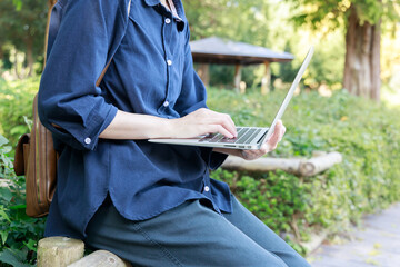 公園でノートパソコンを使用している女性　屋外　仕事　イメージ