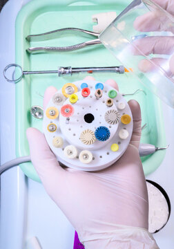 Female dentist holding polishing discs. Resin polishing kit, dental resin polisher, sanding bristle disc, dental polishing discs. Dental instrument tray. Close-up, closed angle.