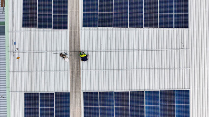 Aerial view of a rooftop with solar panels, showing a technician in safety gear performing maintenance. The scene highlights renewable energy, solar technology, and sustainable infrastructure.