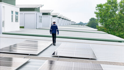 A technician in safety attire walks on a metal rooftop lined with solar panels, performing an inspection. The scene emphasizes renewable energy, sustainable infrastructure, and solar maintenance.