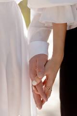 A couple in love touches each other with their hands. Love story of a young couple in love. Wedding rings on ring fingers. Concept of a marriage proposal. Starting a family.
