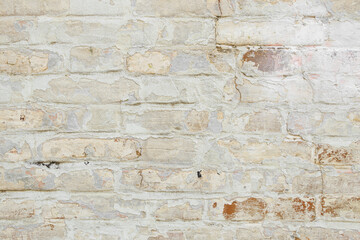 Beige grungy brick wall. Free space for an inscription. Can be used as a background or poster. Fragment of a wall with bumps and shabby plaster.