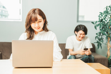 家でテレワークする男女（女性・笑顔）
