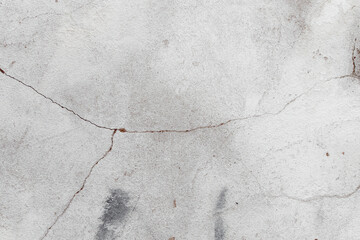 Obraz premium White texture of a concrete wall with natural relief and damage in the form of chips and scratches. Fragment of an old stone surface with a crack. Dark rough surface with a place for an inscription