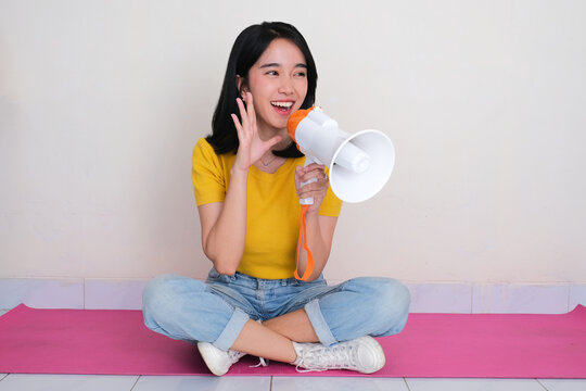 A women sitting cross legged on the floor telling something using megaphone