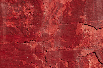 Red texture of a concrete wall with natural relief and damage in the form of chips and scratches. Fragment of an old stone surface with a crack. Dark rough surface with a place for an inscription