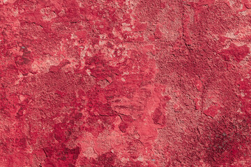 Red texture of a concrete wall with natural relief and damage in the form of chips and scratches. Fragment of an old stone surface with a crack. Dark rough surface with a place for an inscription
