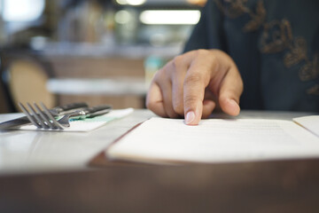 women hand reading a food menu at cafe.