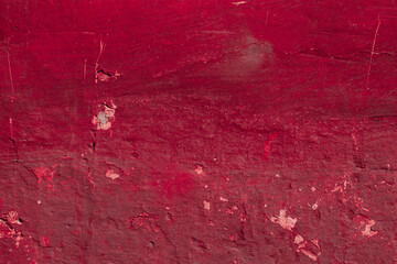 Red texture of a concrete wall with natural relief and damage in the form of chips and scratches. Fragment of an old stone surface with a crack. Dark rough surface with a place for an inscription