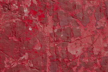 Red texture of a concrete wall with natural relief and damage in the form of chips and scratches. Fragment of an old stone surface with a crack. Dark rough surface with a place for an inscription