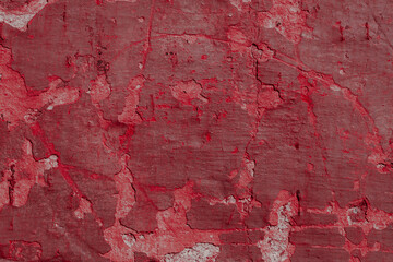 Red texture of a concrete wall with natural relief and damage in the form of chips and scratches. Fragment of an old stone surface with a crack. Dark rough surface with a place for an inscription