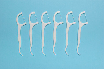 White Dental Floss Picks Arranged in Parallel on Blue Background for Oral Hygiene