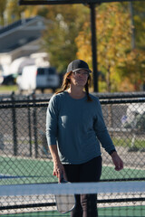 woman playing pickle ball with black paddle on outdoor pickleball courts