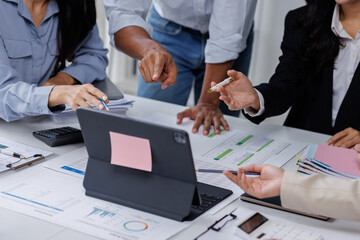 Group of confident business people point to graphs and charts to analyze market data, balance sheet, account, net profit to plan new sales strategies to increase production capacity.	