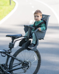 Portrait of Caucasian little boy on bicycle chair. Vertical photo. 