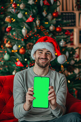  Portrait of a christmas man in santa hat holding smartphone with green screen