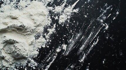 A top view of a black background with sprinkled flour creating a baking ambiance There is ample copy space in the image