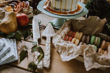 A rustic-themed dessert table featuring an elegant caramel drizzled cake, colorful macarons, fresh fruits. The wooden table setting creates a cozy and inviting atmosphere for a delightful gathering