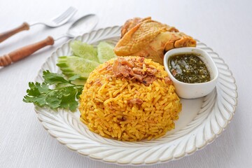 Chicken Biryani rice toped Fried shallots, yellow rice in white plate on white background, thai called khao mok gai