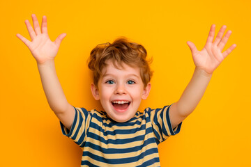 excited smiling little boy with his hands up on bright studio background