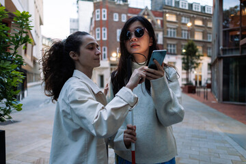 Woman helping blind friend using navigation app on smartphone